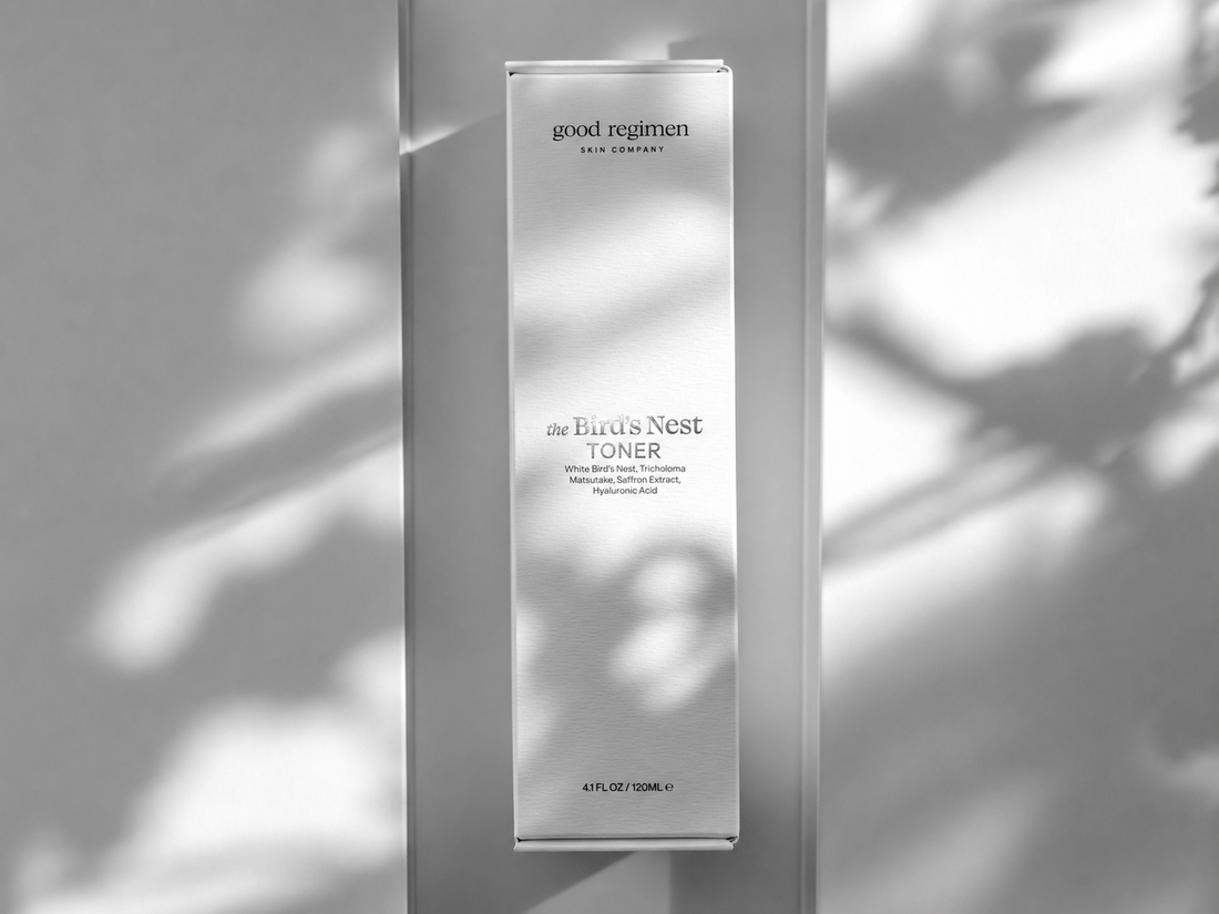 Good Regimen The Bird’s Nest Toner box with strong metallic silver product label in a luxury minimalist skincare image with soft leaf shadows.
