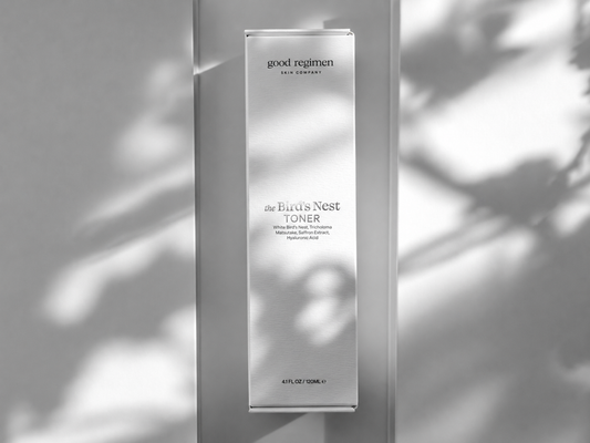 Good Regimen The Bird’s Nest Toner box with strong metallic silver product label in a luxury minimalist skincare image with soft leaf shadows.