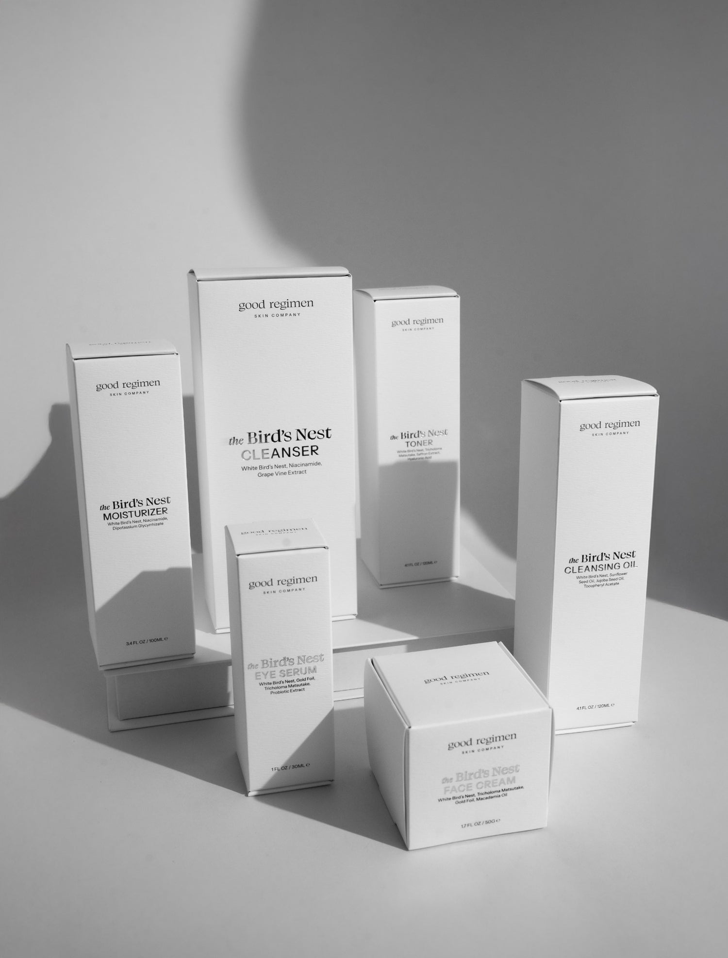 Good Regimen Bird’s Nest skincare collection in white product boxes, featuring moisturizer, eye serum, cleanser, face cream, toner, and cleansing oil in a clean minimalist studio setting with soft shadows.